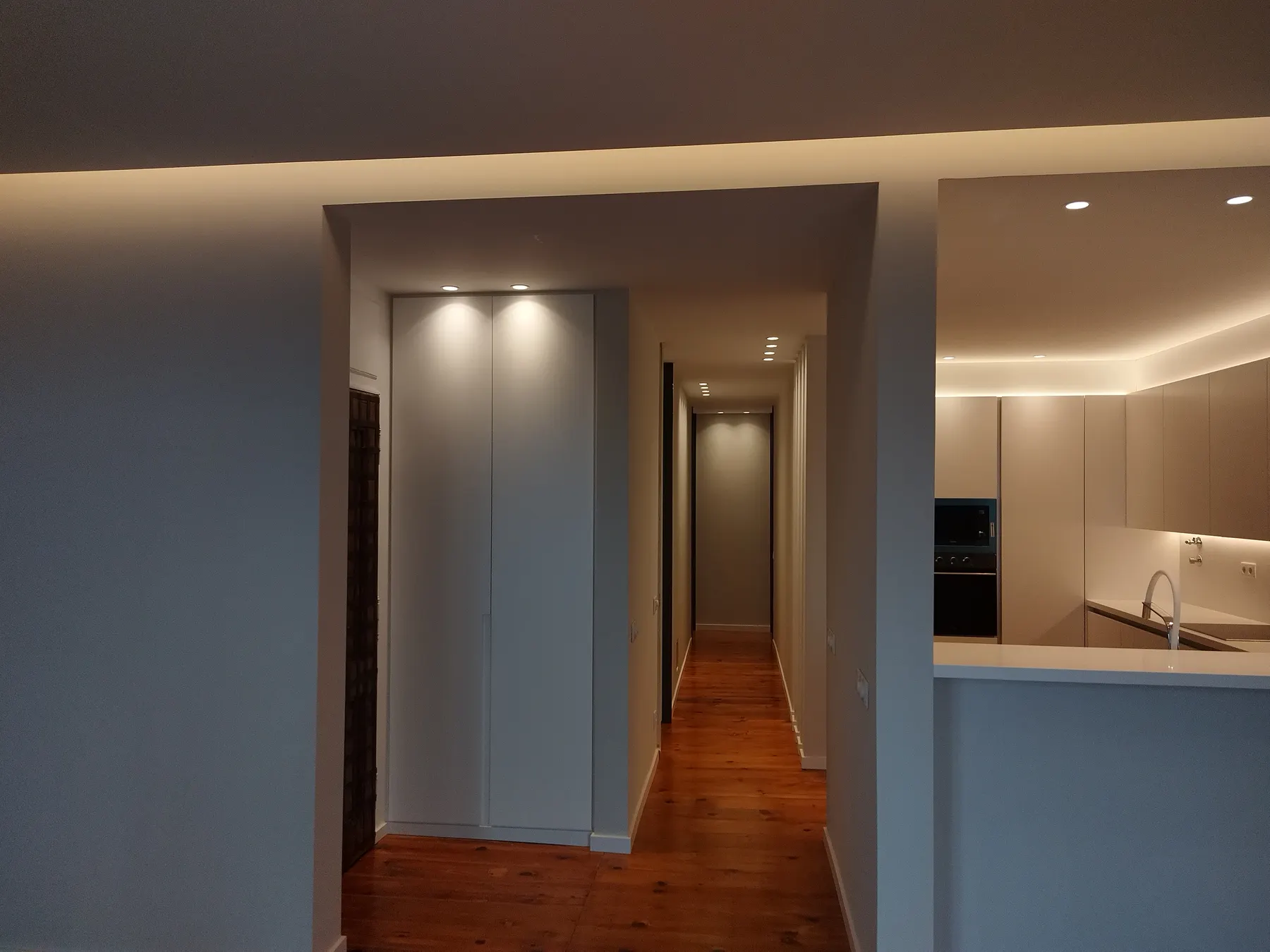 Corredor e cozinha remodelados pela Autentifuturo, com luz quente embutida